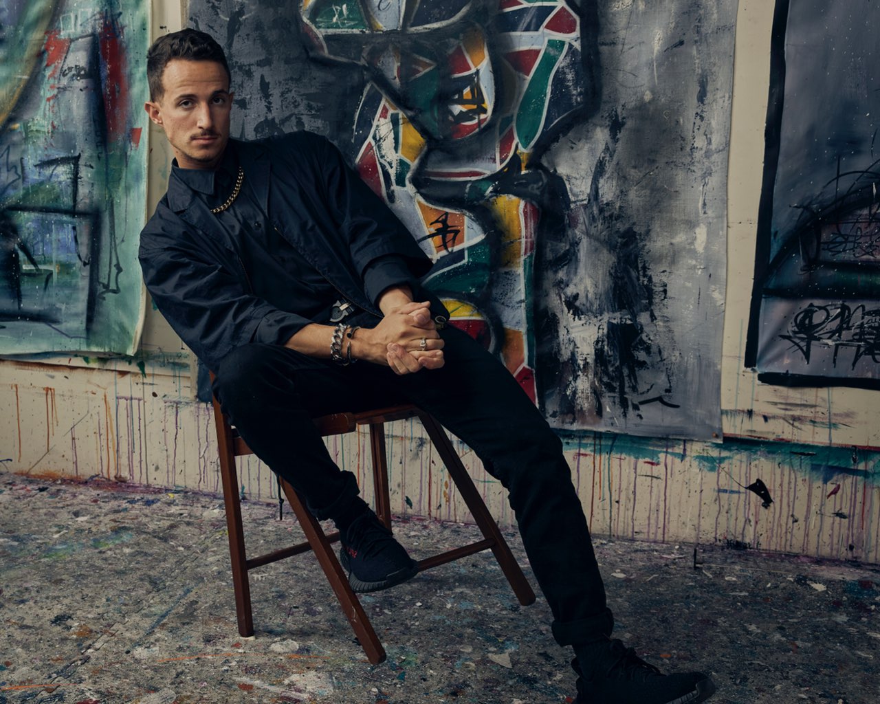 Joe Taveras seated in his art studio, surrounded by paintings